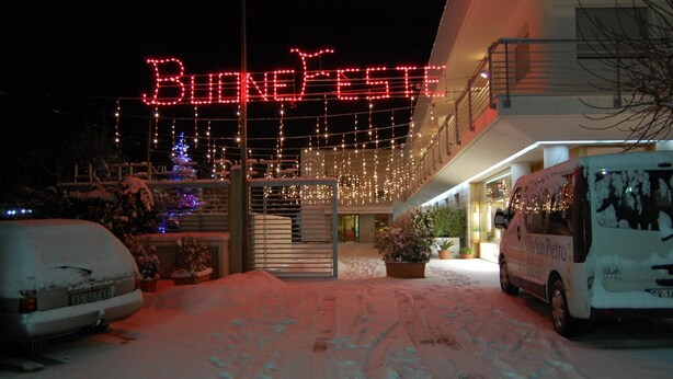 A hotel entrance with a snow-covered driveway and a sign reading "BUOND FESTE". - Hotel Villa San Pietro (San Giovanni Rotondo)