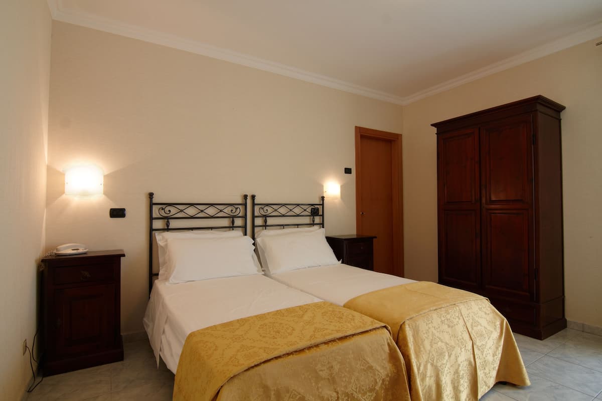 Una cama doble con dos mesitas de noche, un armario y una lámpara de pared.