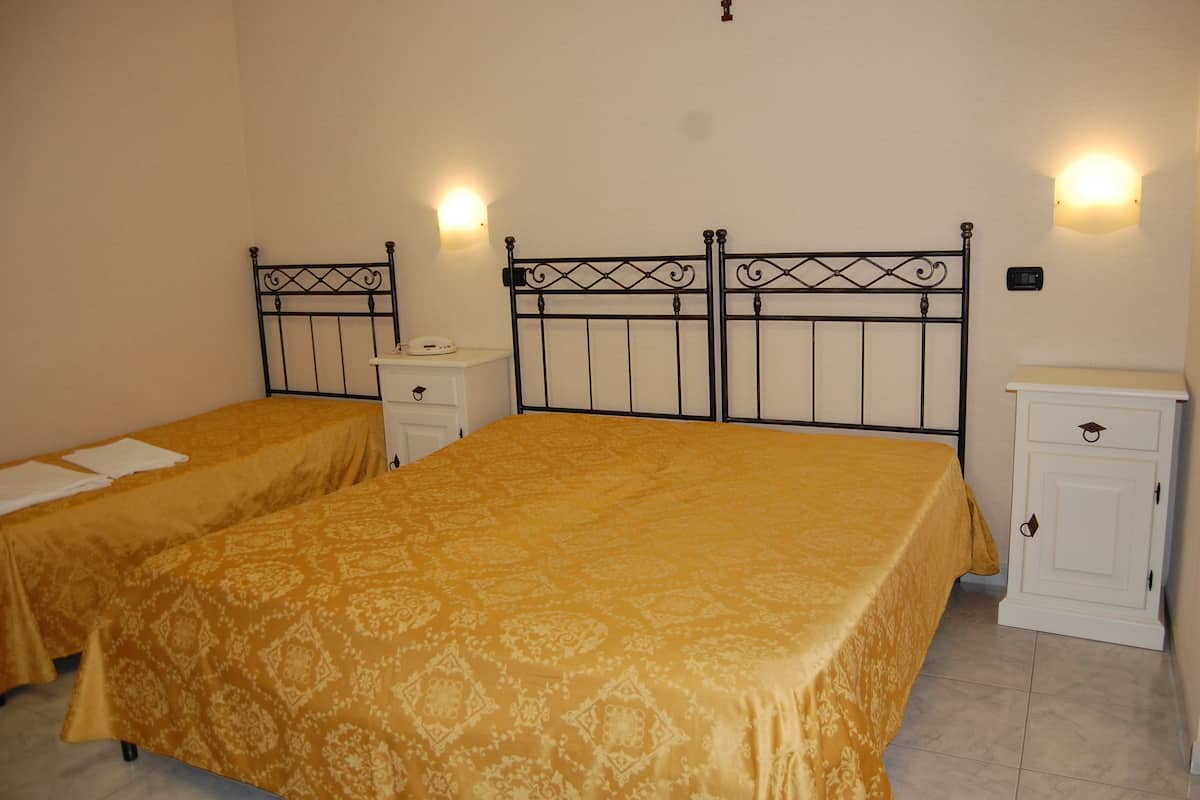 Una habitación con dos camas individuales, cada una con cabecera y mesita de noche.