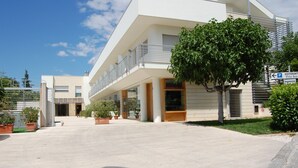 A modern building with a flat roof, large windows, and a covered outdoor area with potted plants. - Hotel Villa San Pietro (San Giovanni Rotondo)