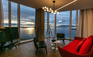 A modern room with large windows, a tripod, and a red sofa. - Tower Suites Reykjavik (Reykjavik)