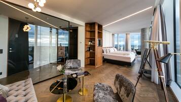 Una sala de estar moderna con una cama grande, un muro de vidrio y vistas a la ciudad.