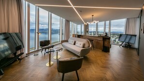 A spacious living room with a large window, a sofa, a coffee table, and a TV. - Tower Suites Reykjavik (Reykjavik)
