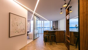 A modern kitchen with a wooden countertop, bar stools, and a view of the sea. - Tower Suites Reykjavik (Reykjavik)