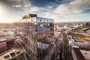 A high-rise building with a glass facade and a view of the city below. - Tower Suites Reykjavik (Reykjavik)
