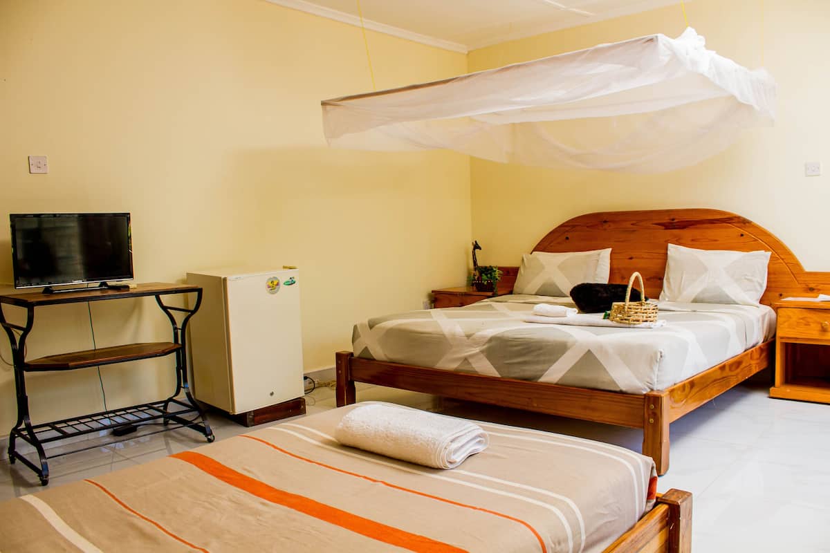 Quarto com cama, mesa de cabeceira e televisão sobre um móvel.