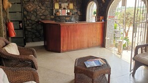Un área de recepción con un escritorio de madera, paredes de piedra y un amplio ventanal en arco.