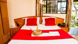 Una cama bien hecha con ropa de cama roja y blanca, una cesta con una cuchara y una toalla sobre la cama.