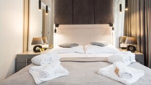 Ein modernes Hotelzimmer mit einem großen Bett, zwei Nachttischen mit Lampen und einem Kopfteil.