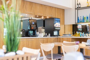 A modern kitchen with a coffee machine, a refrigerator, and a wine bottle shelf.