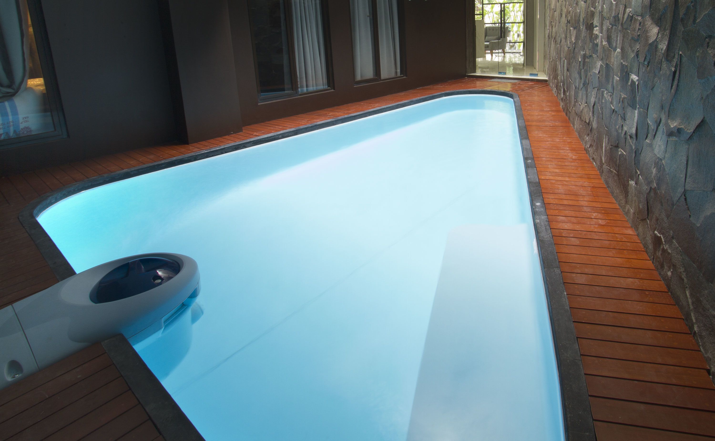 A modern indoor swimming pool with a wooden deck surrounding it.