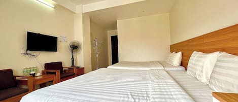 A hotel room with a large bed, a TV mounted on the wall, a desk with a chair, and a coat rack.