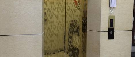 A modern elevator with a patterned door and a digital display.