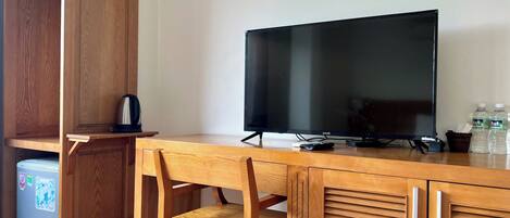 Un escritorio de madera con un televisor, una silla y un refrigerador pequeño.