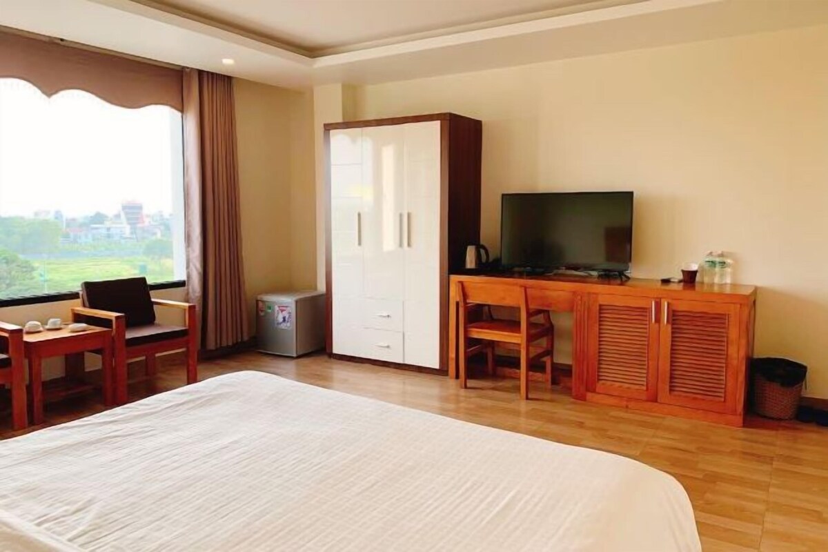 Une chambre d’hôtel avec un grand lit, un bureau avec une télévision, une armoire et une vue sur l’extérieur.