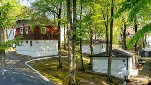 Une rangée de maisons de plain-pied avec des garages attenants, entourées d’arbres et bordées d’une allée pavée.