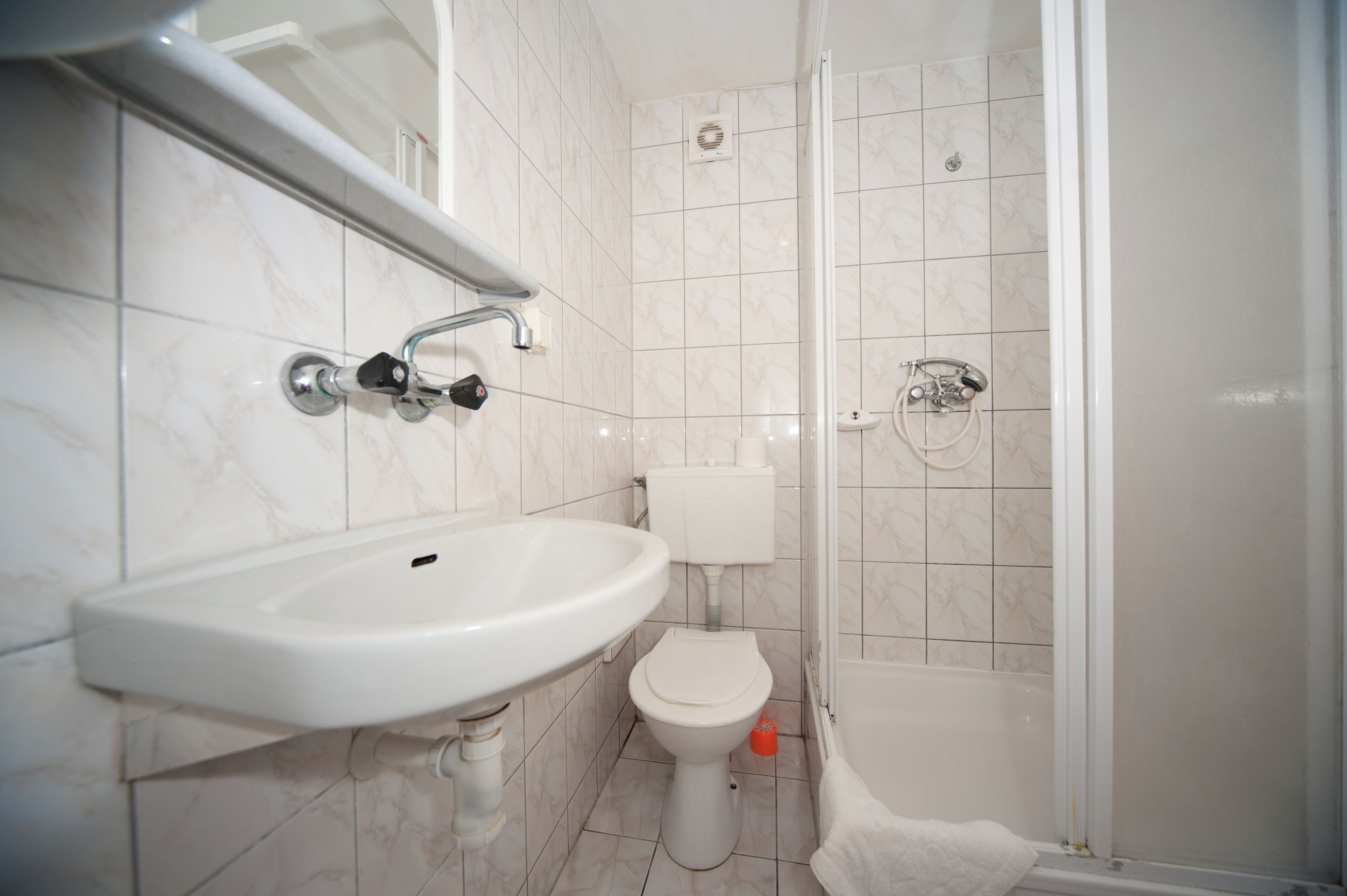 A bathroom with a white sink, toilet, and shower.