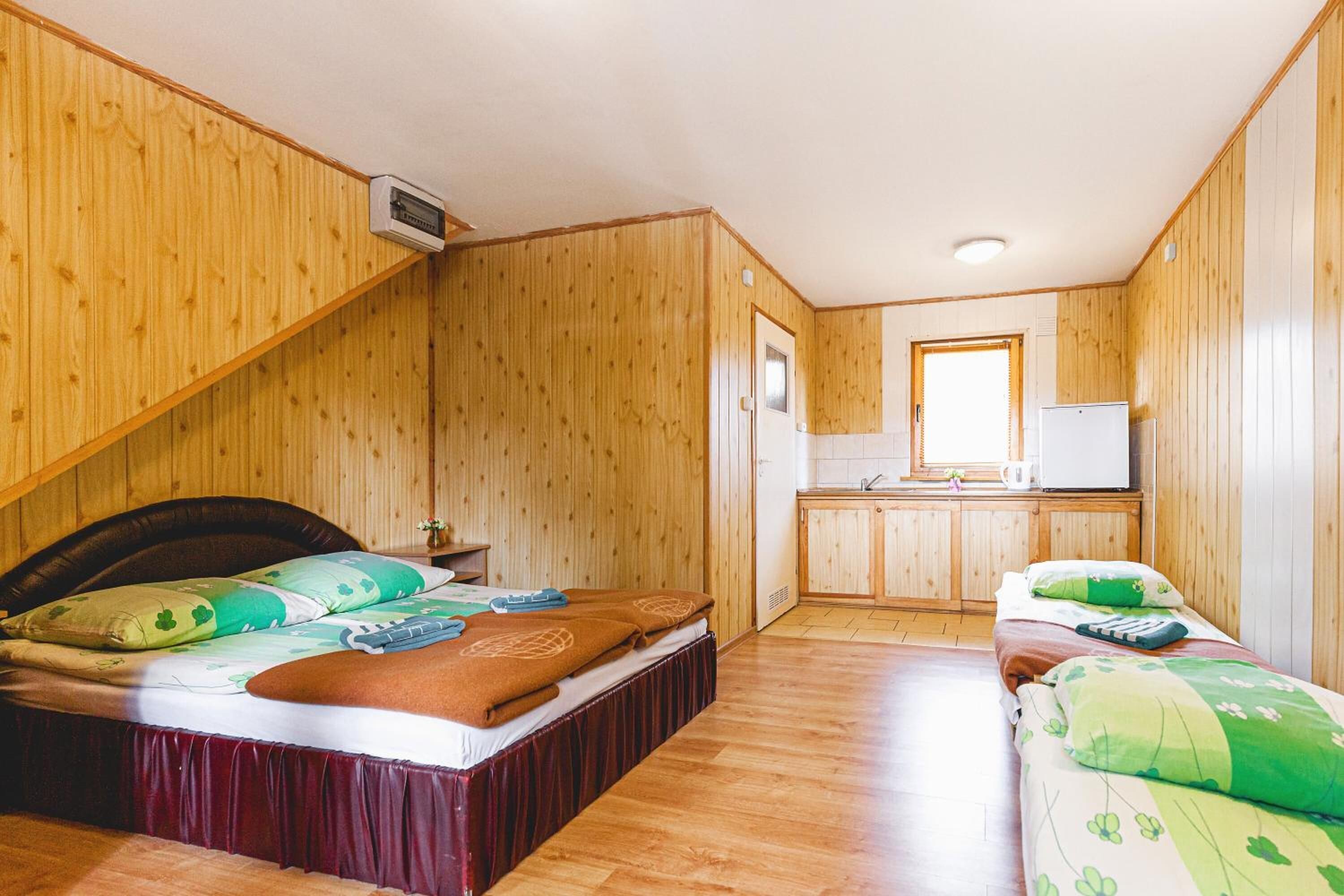 A wooden-paneled room with a bed, a small kitchenette, and a mirror.