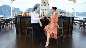A couple seated at a bar with a view of mountains. - Paradise Elegance Cruise (Tuan Chau)
