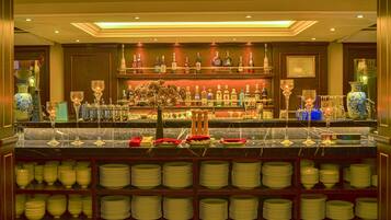 A bar area with shelves of liquor bottles, a marble countertop, and stacks of plates.