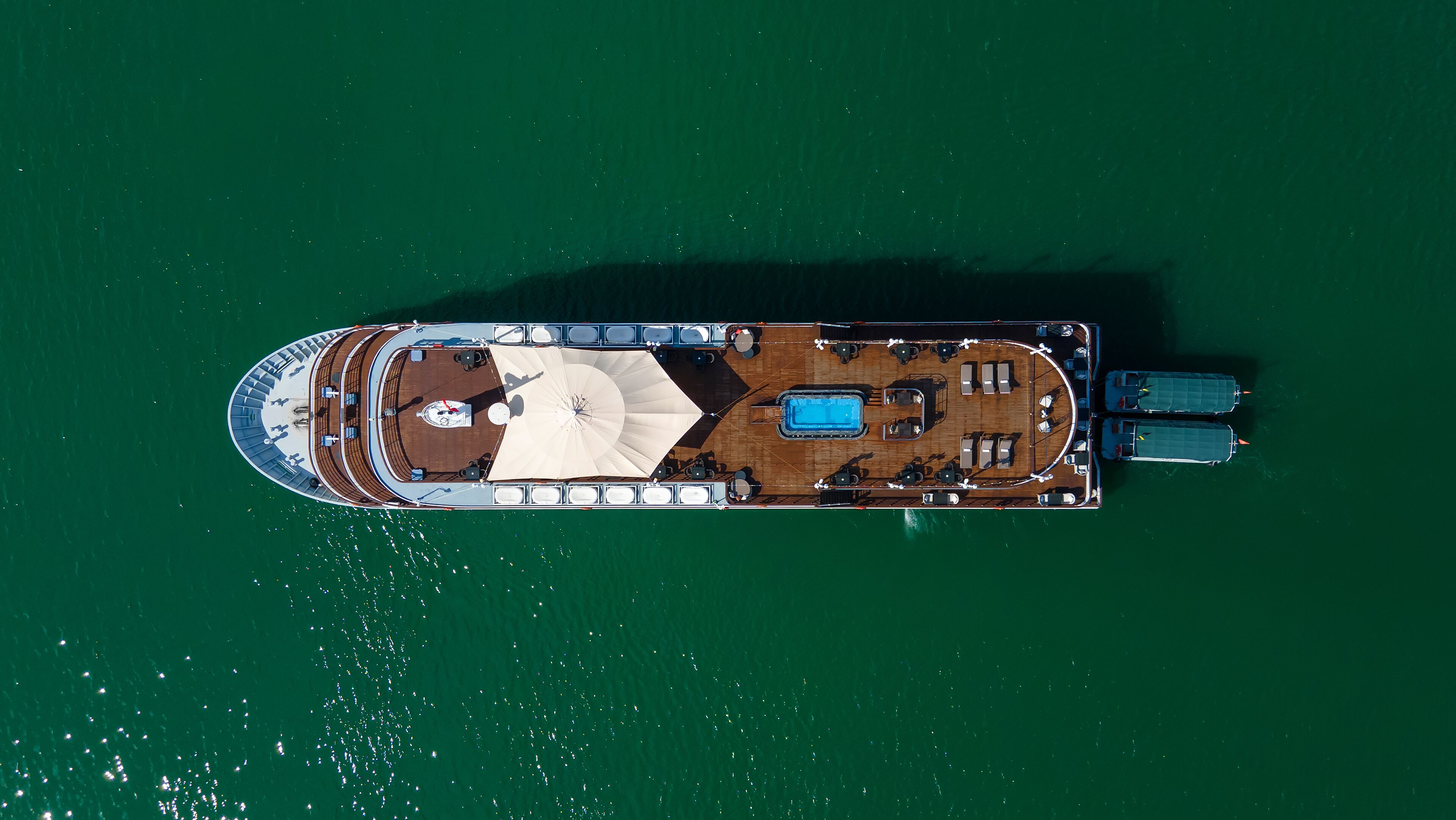 An aerial view of a yacht with a swimming pool, sun loungers, and a dining area.