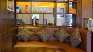 A leather sofa with patterned cushions, a wooden coffee table, and a bookshelf filled with books and decorative items.