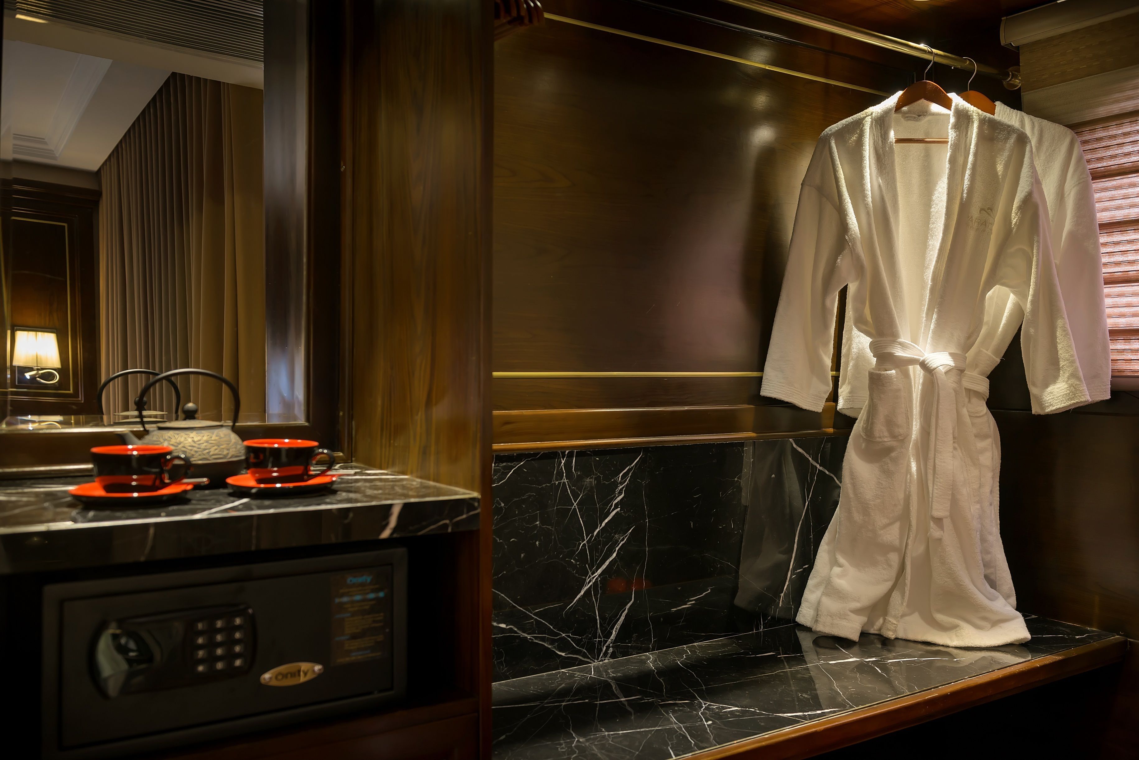 A bathroom with a marble sink, a robe hanging on the wall, and a towel rack.