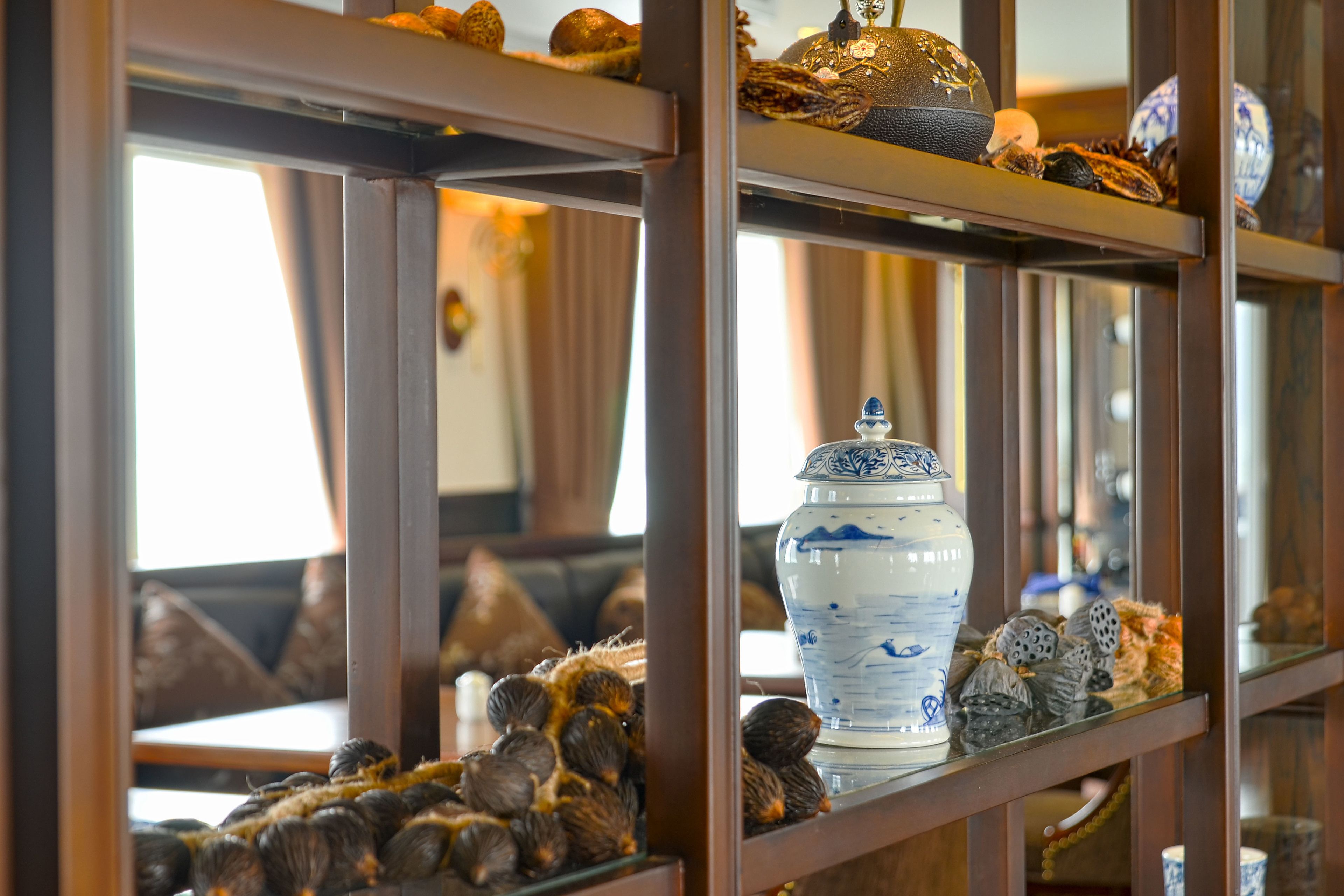 Una repisa con objetos decorativos, incluyendo un jarrón blanco con diseños azules, un adorno dorado y varias figuritas pequeñas.