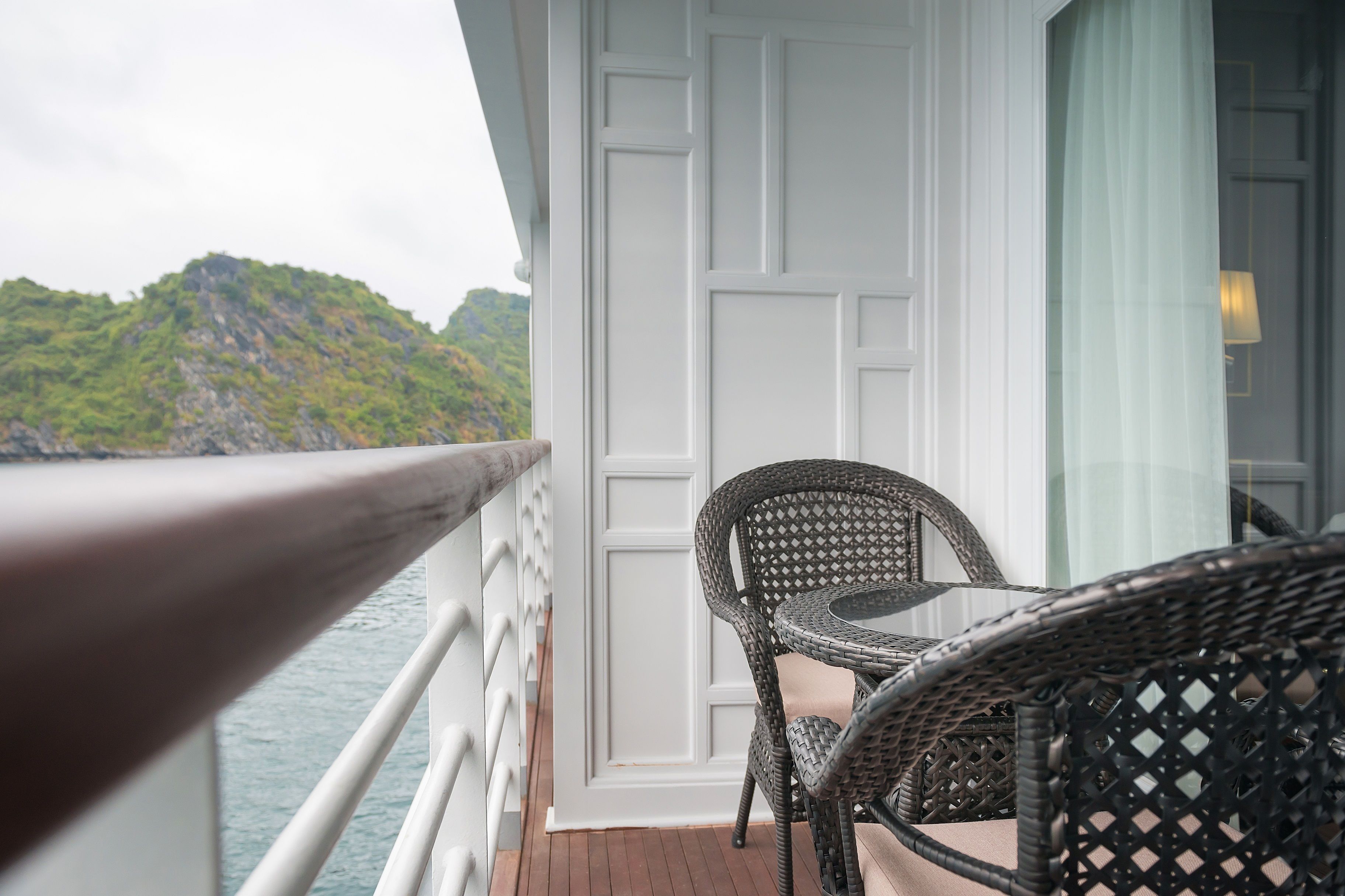 A balcony with wicker furniture and a view of a mountainous landscape.