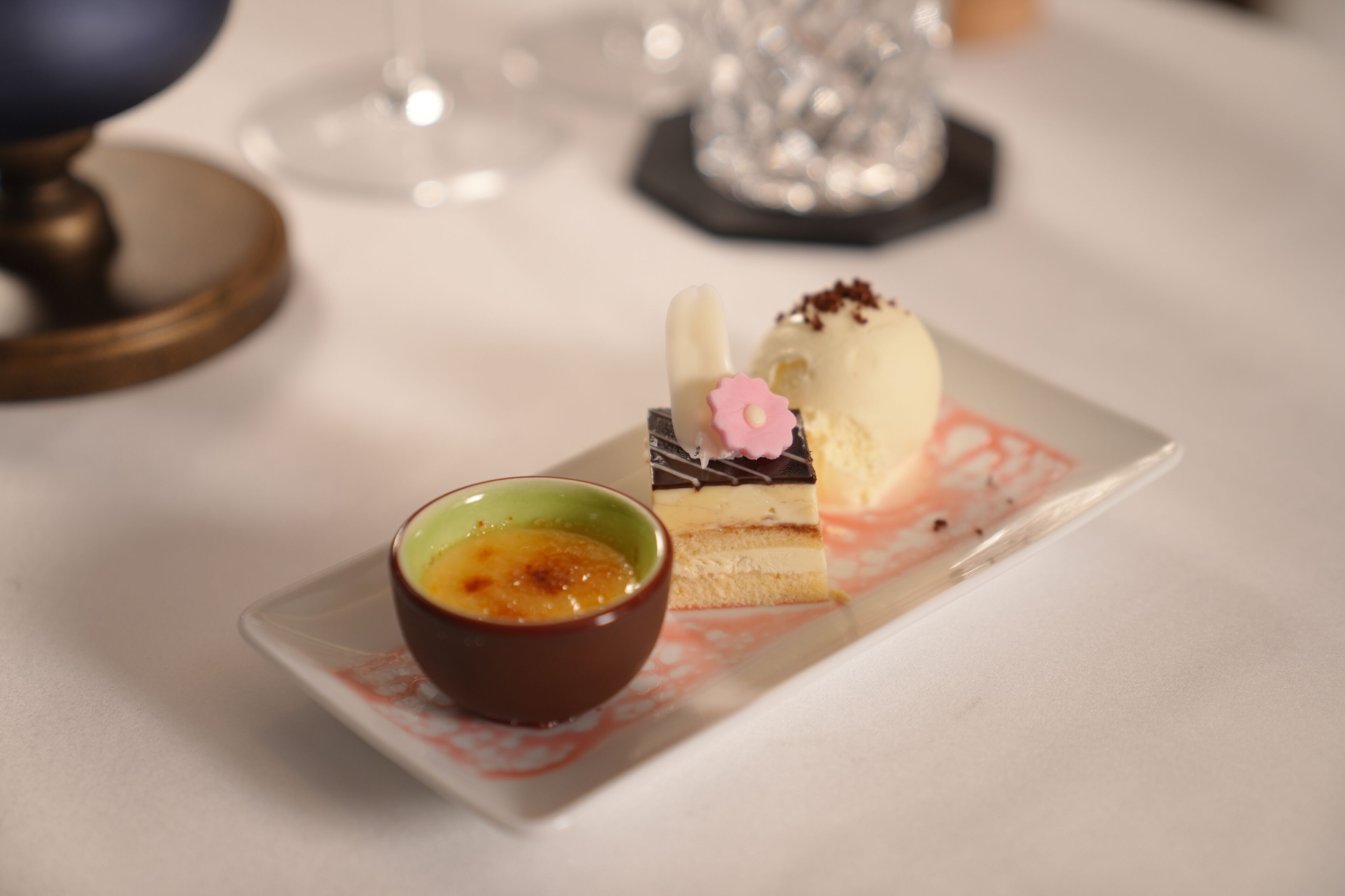 A dessert plate with a slice of cake and a small bowl of sauce.