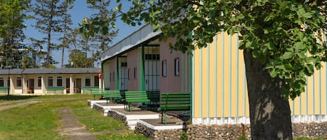 A building with a green bench outside, a tree in front, and a clear sky.