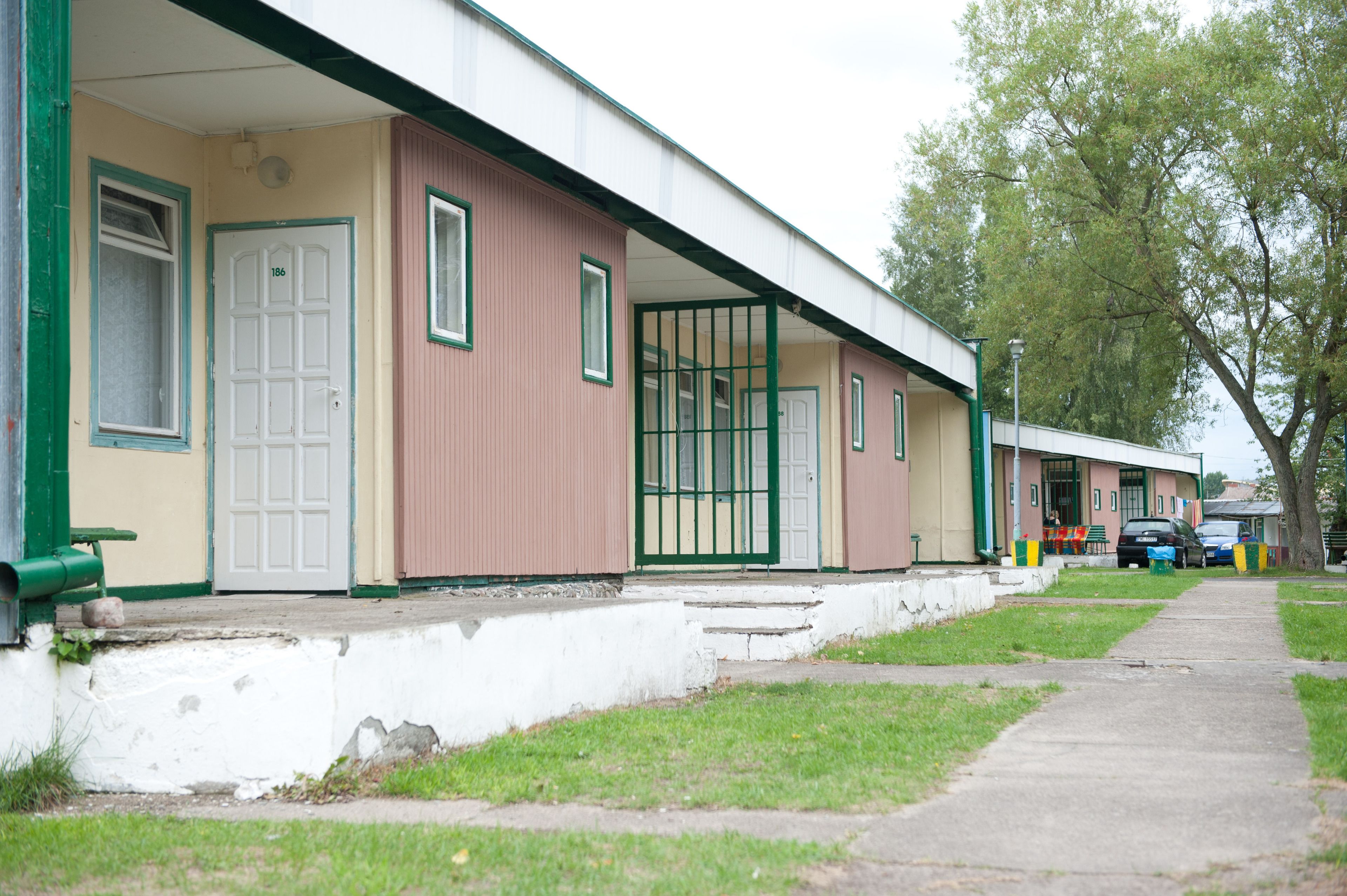 Een rij gelijkvloerse gebouwen met een consistente bouwstijl, herkenbaar aan een plat dak en een eenvoudig gevelontwerp.