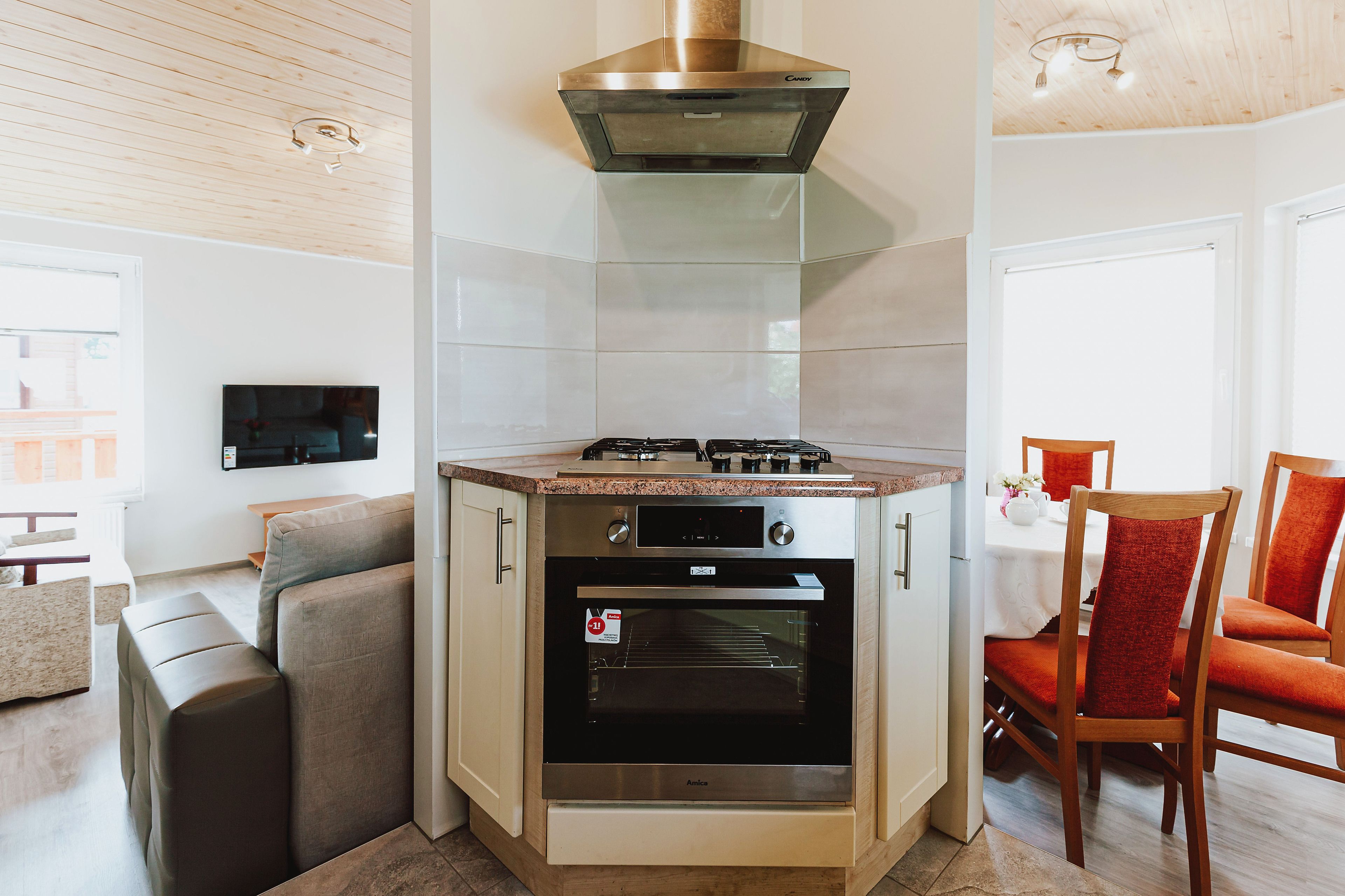 Uma cozinha compacta com forno embutido, fogão a gás e uma coifa moderna de aço inoxidável.