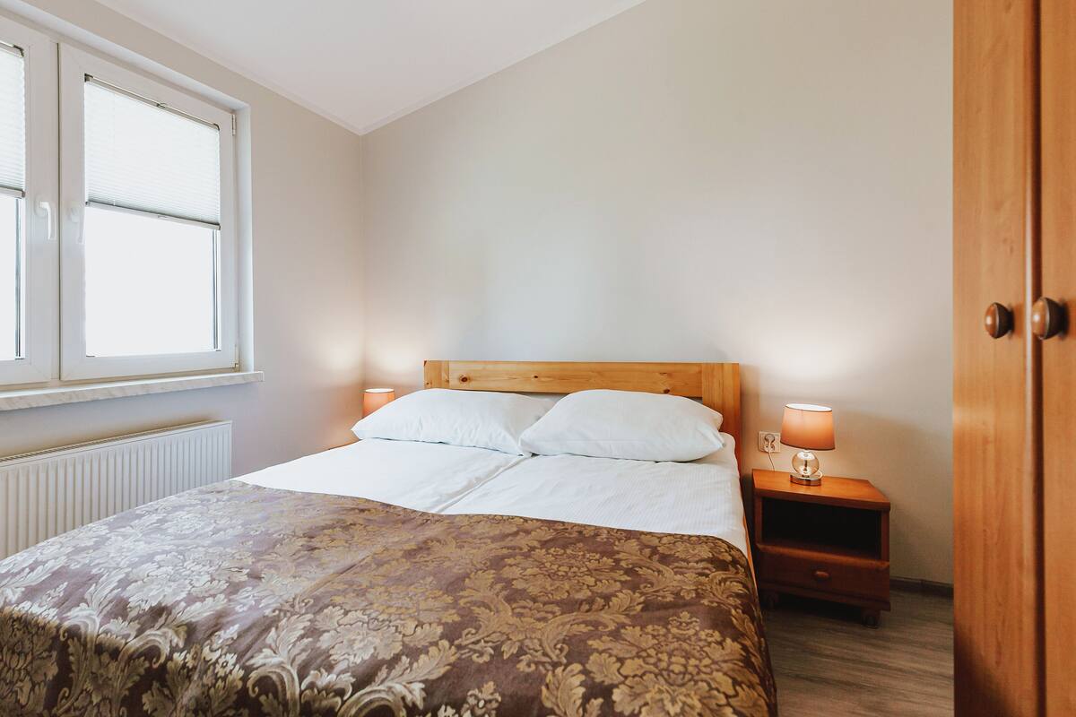 Ein Schlafzimmer mit einem Bett, Nachttischlampen, einem Fenster und einer Heizung.