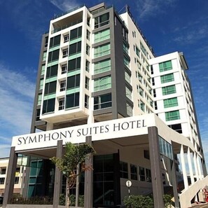 Un hôtel moderne dont le nom, « SYMPHONY SUITES HOTEL », est affiché en grand sur le bâtiment.