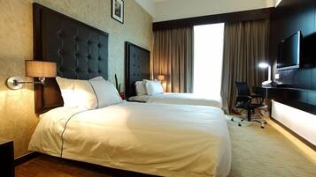 Habitación de hotel con dos camas, televisor, escritorio y una silla.