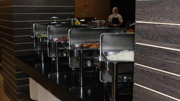 Buffet stations with various food options and a staff member in the background.