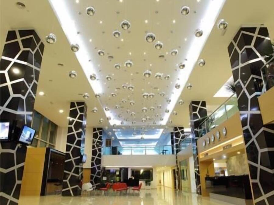 A modern interior with a geometric ceiling design, a central seating area, and a glass railing overlooking the space.