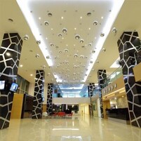 Un interior moderno con un diseño geométrico en el techo, una zona de estar central y una barandilla de cristal con vistas al espacio.