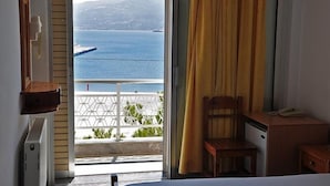 A room with a view of the sea and mountains, a wooden desk, a chair, and a small table with a phone. - Nora Hotel (Sitia)