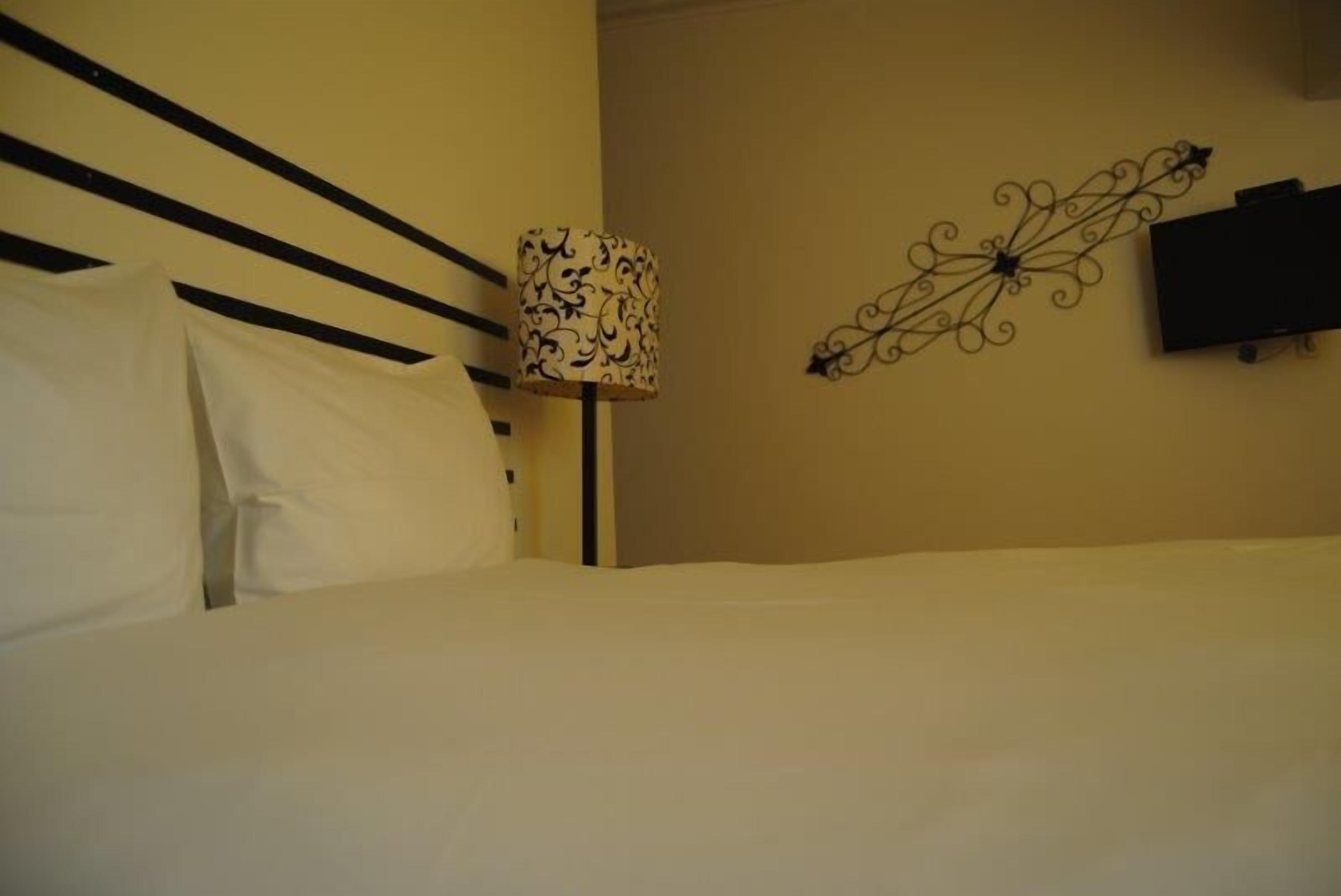 Une chambre d’hôtel avec un lit, une lampe et un téléviseur fixé au mur.