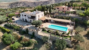 Una villa con piscina, rodeada de olivos y un paisaje montañoso.