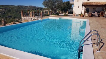 Una piscina al aire libre de temporada, sombrillas