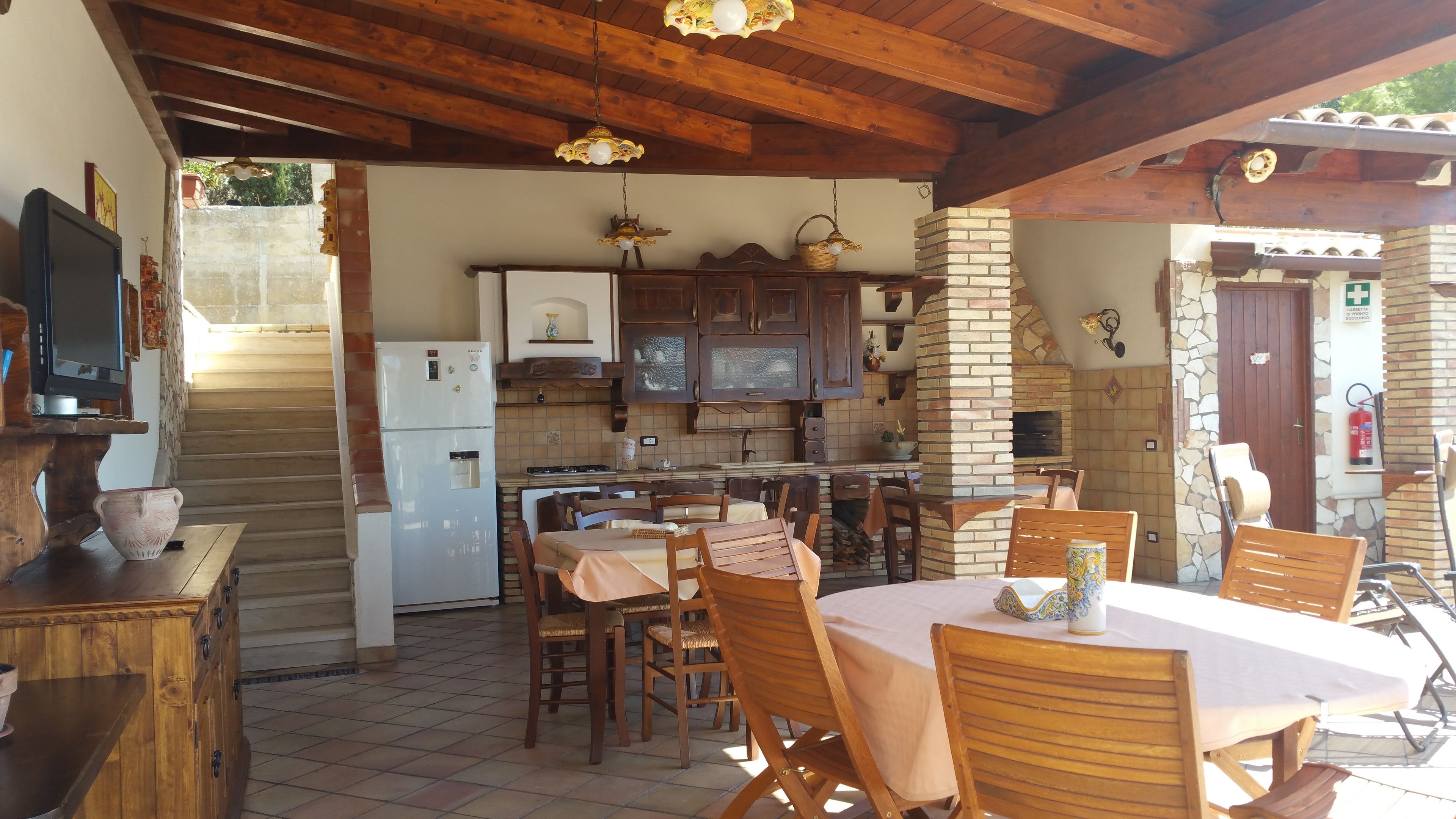 A rustic kitchen with wooden cabinets, a brick fireplace, and a dining area with wooden tables and chairs.
