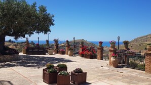 Una terraza con plantas en macetas, un banco y vista al mar.