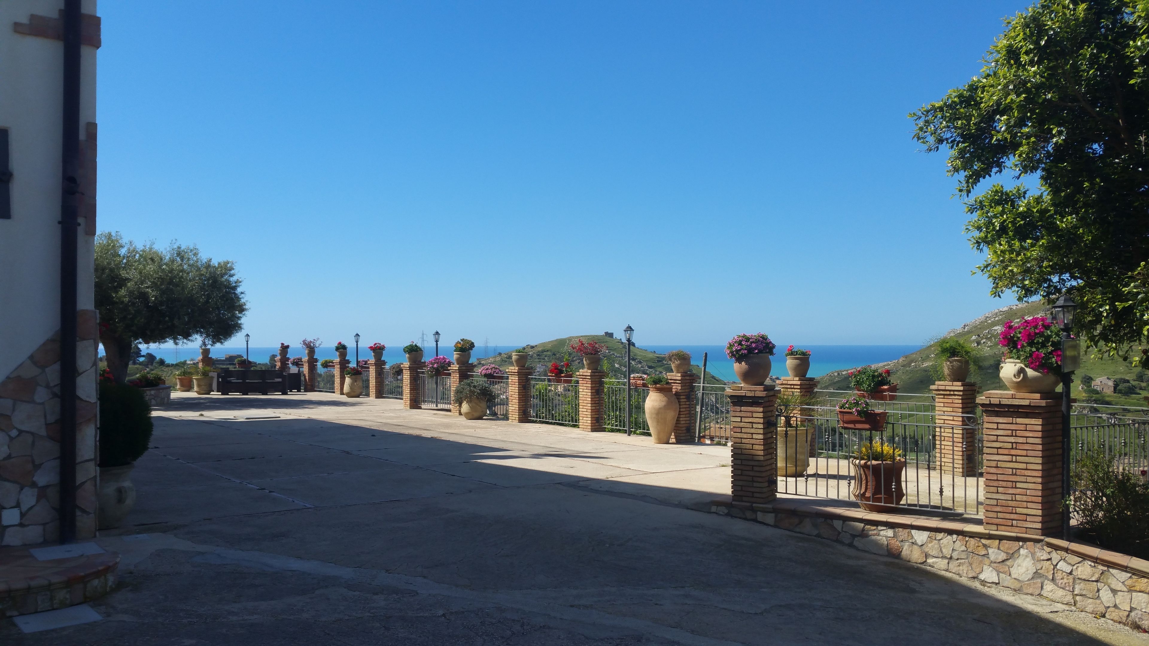 Ein gepflasterter Weg führt zu einem Steinhaus mit Blick auf das Meer.