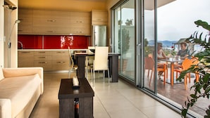 Eine moderne Küche mit Holzschränken und einer roten Spritzschutzwand, ein Essbereich mit orangefarbenen Stühlen und eine große Schiebeglastür zu einer Außenpatio mit ebenfalls orangefarbenen Stühlen.