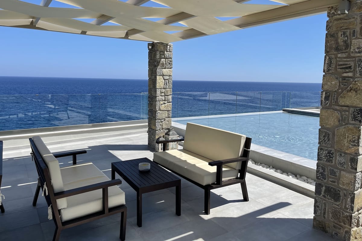 An outdoor seating area with a stone pillar, a bench, and a small table.