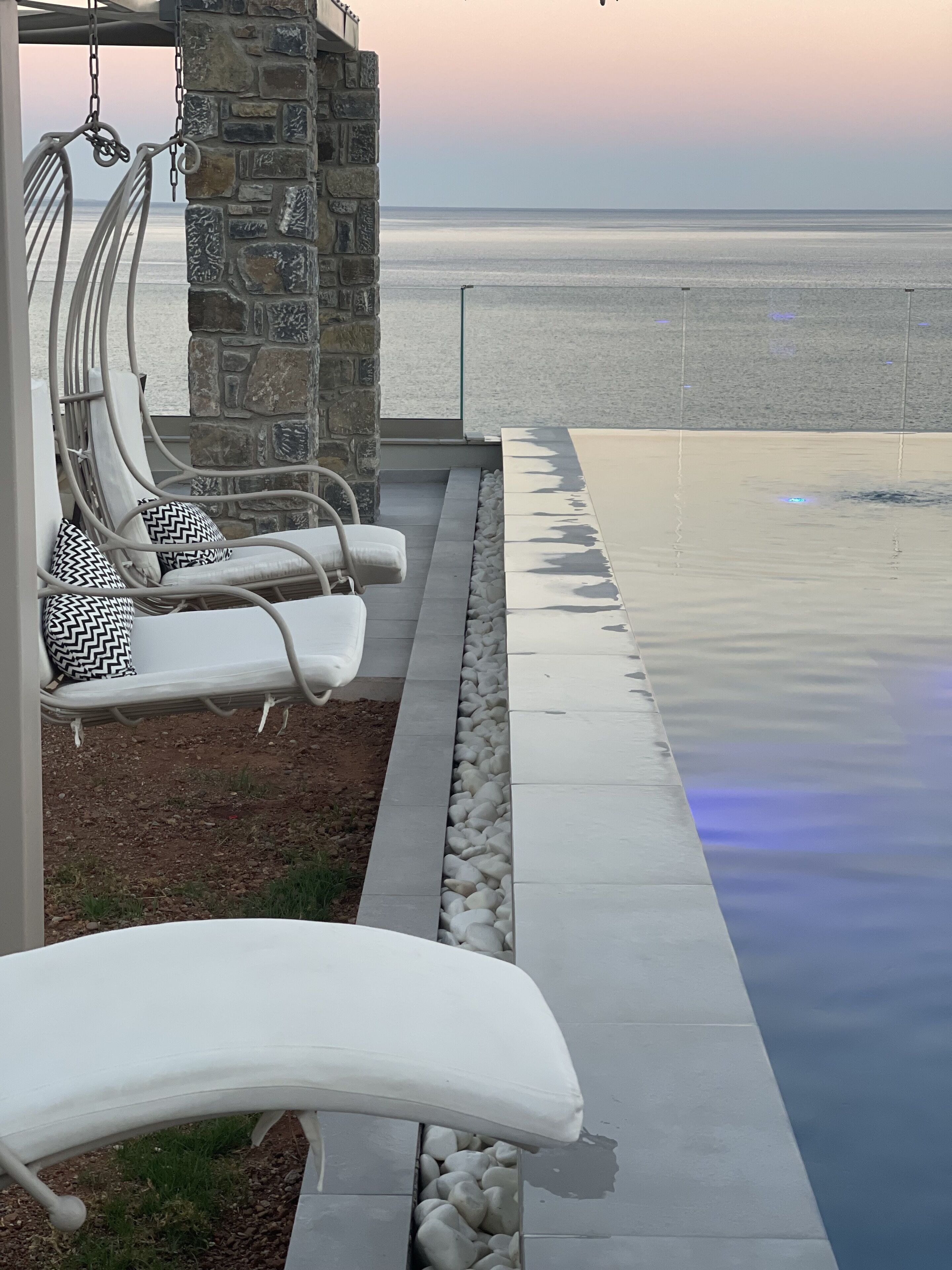 Zona junto a la piscina con sillones de descanso y una pared de piedra.