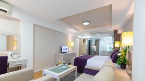 A hotel room with a bed, a desk with a computer, a coffee maker, a glass table, and a plant. - Hotel M (Belgrade)